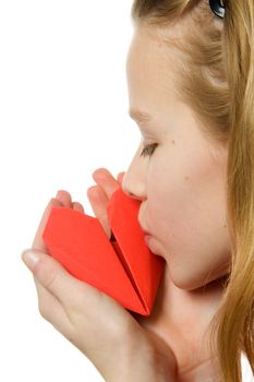 Young blonde girl kissing red heart made out of paper over white background