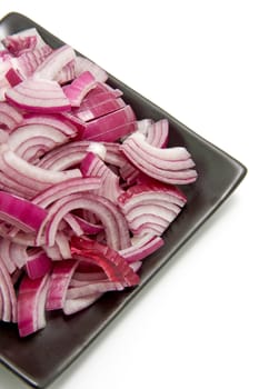 black plate with sliced red onion isolated on white background