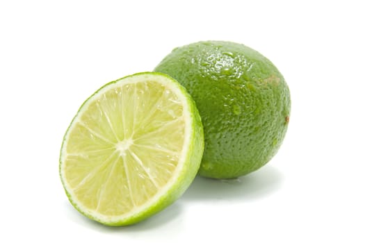 fresh juicy green lime, one whole and one half, with waterdrops. Isolated on white background