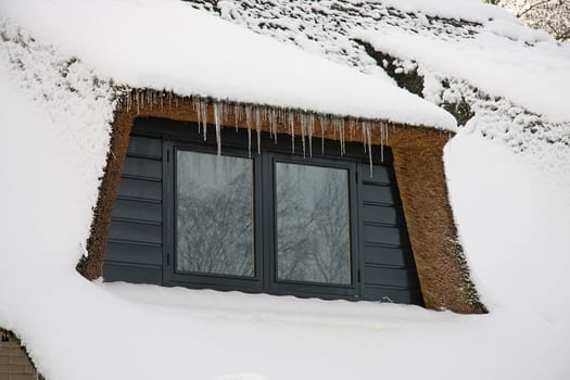 window of a house with icicles in winter time