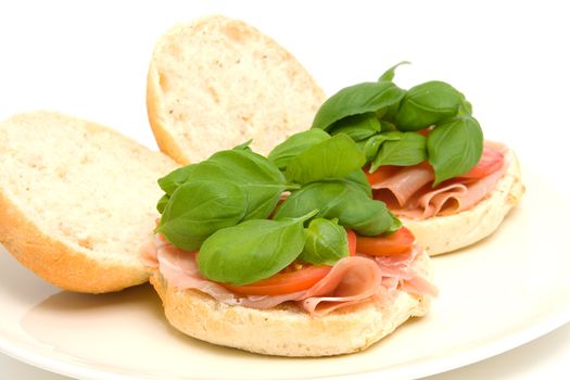 Fresh healthy sandwich with basil and tomatoes on plate over white background