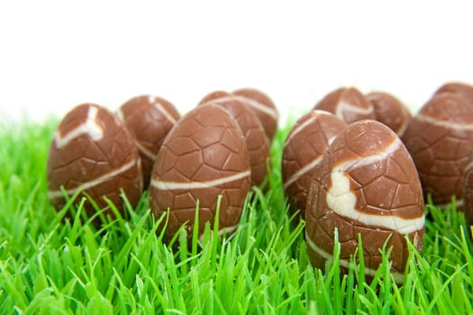 chocolate easter eggs in grass over white background