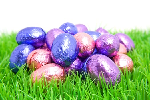 colorful chocolate easter eggs on grass over white background