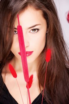 Portrait of a pretty long hair woman behind red plant