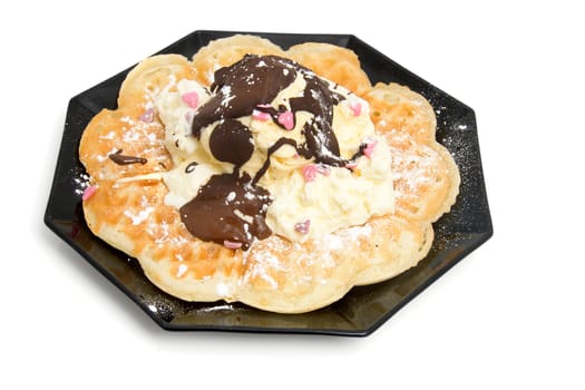 delicious dessert with waffle and ice cream on black plate over white background