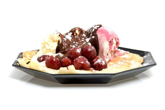 delicious dessert with waffle and ice cream on black plate over white background