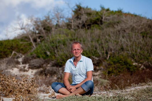 young man is relaxing outdoor in dune in summer vacation