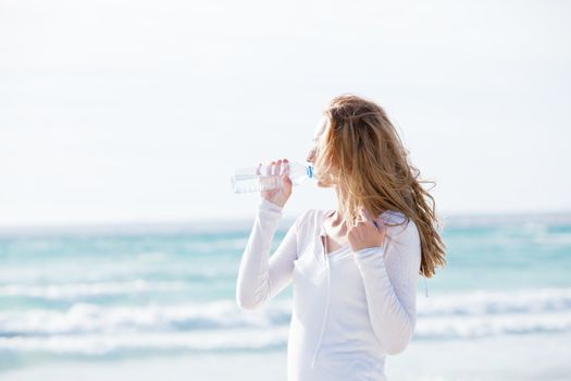 beautiful young woman drinking water in summer beach outdoor