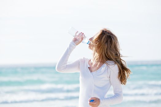 beautiful young woman drinking water in summer beach outdoor