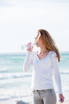 beautiful young woman drinking water in summer beach outdoor