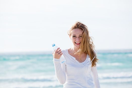 beautiful young woman drinking water in summer beach outdoor