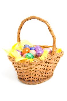 Cane basket with chocolate easter eggs over white background