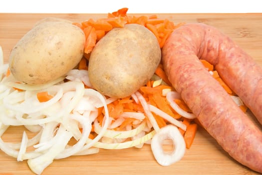 Ingredients for Dutch hutspot stew on wooden cutting board over white background