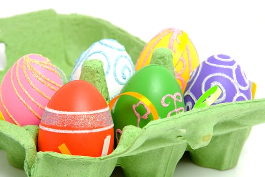 Colorful easter eggs in green carton box over white background