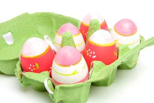 Pink easter eggs in green carton box over white background