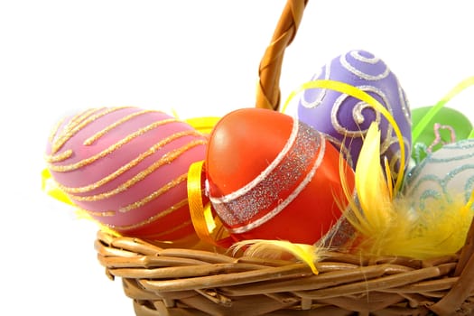Cane basket with colorful easter eggs over white background