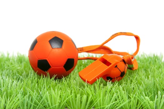 Orange soccer ball ans flute on grass over white background
