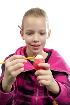 Girl is painting easter egg over white background
