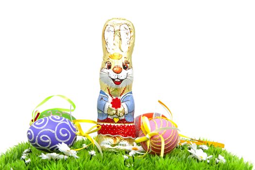 Chocolate easter bunny and colorful eggs on grass over white background