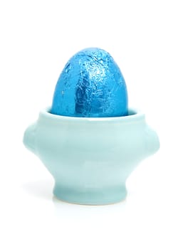 Blue easter egg in cup over white background