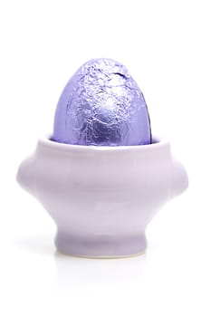 Purple easter egg in cup over white background