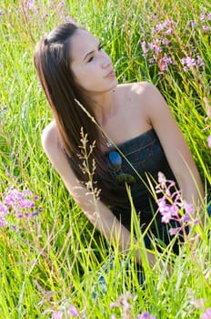 Outdoor shot of beautiful brunette woman sitting in field