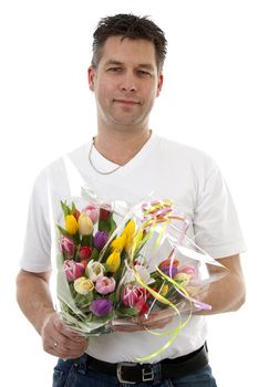 Young man is giving bouquet of colorful tulips over white background