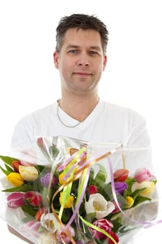 Young man is giving bouquet of colorful tulips over white background
