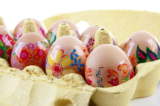 decorated chickens eggs made by children in carton over white background