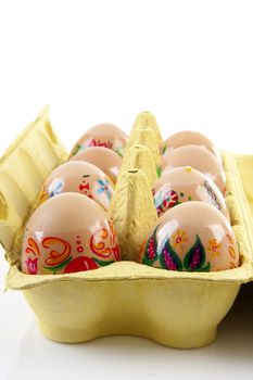 decorated chickens eggs made by children in carton over white background
