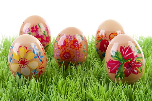 decorated chickens eggs made by children in grass over white background