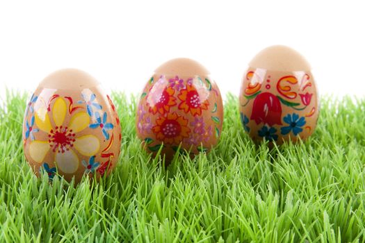 decorated chickens eggs made by children in grass over white background