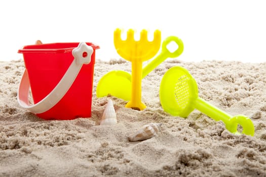colorful plastic toys for the beach on sand over white background