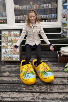 Girl with big typical wooden shoes before souvenis shop in Marken, the netherlands
