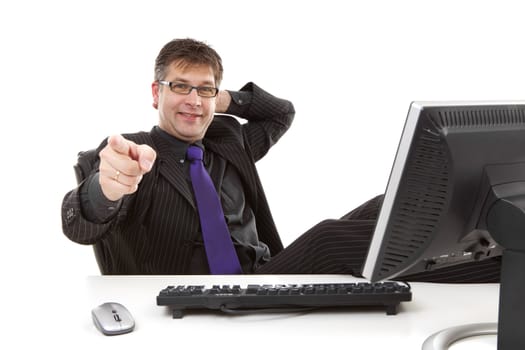 Businessman sitting behind desk is pointing at you over white background