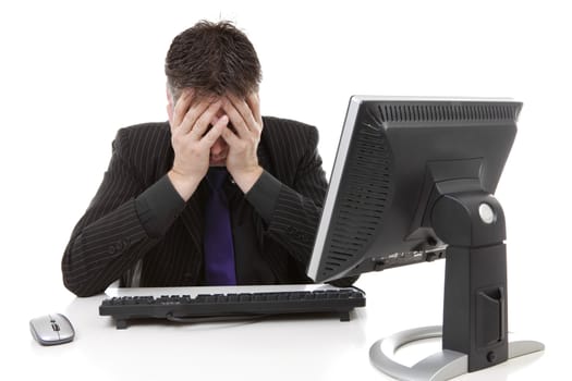 Businessman sitting behind desk is in despair, covering his eyes, over white background