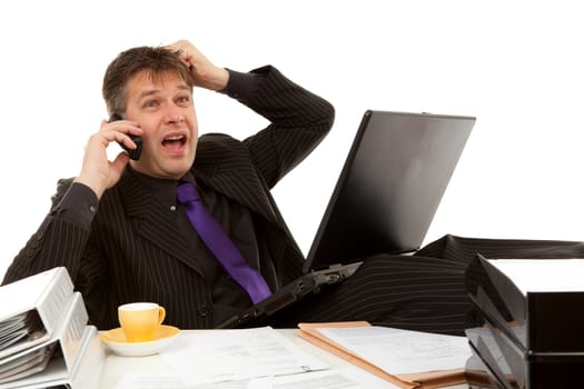 Businessman sitting behind desk is in despair, pulling his hair, over white background