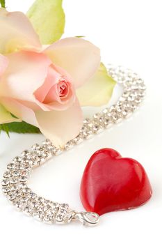 symbolic love and romance with rose, bonbon hart and diamond necklace over white background