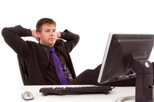 Businessman is sitting relaxed with feet on desk, looking at monitor over white background