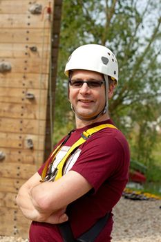 Adult men with helmet is posing before climbing wall