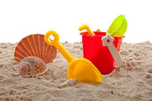 plastic toys for beach and shell on sand over white background