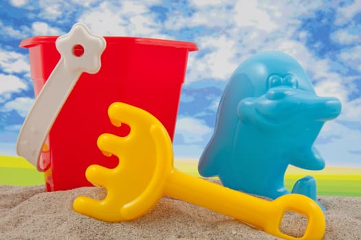 plastic toys for the bach in sand against cloudy blue sky