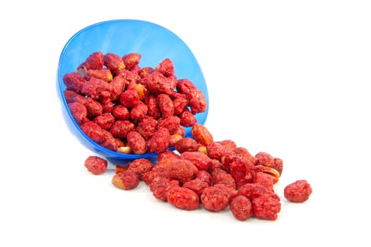 Sugared peanuts fallen out of blue bowl over white background