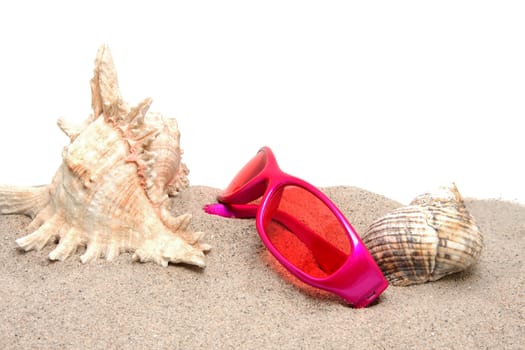 Pink sunglasses on the beach with shells