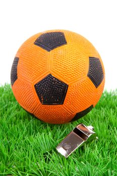 Orange soccer ball and flute on grass over white background