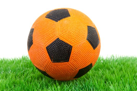 Orange soccer ball on grass over white background
