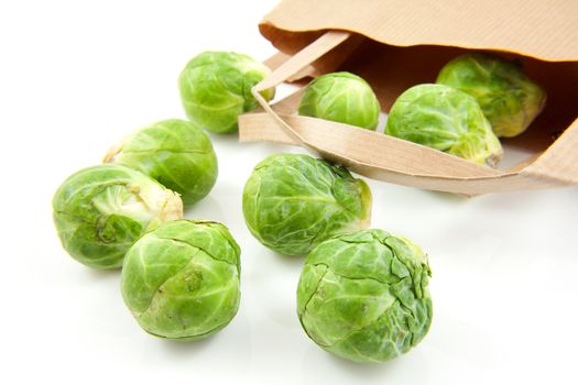 Brussels sprouts fallen out of paper bag over white background