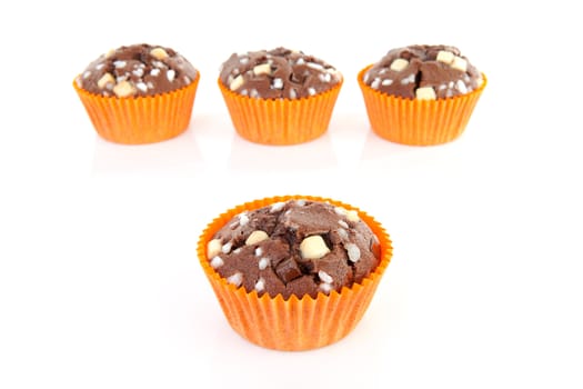 four brown home baked cupcake with chocolate pieces, focus on front, isolated on white background