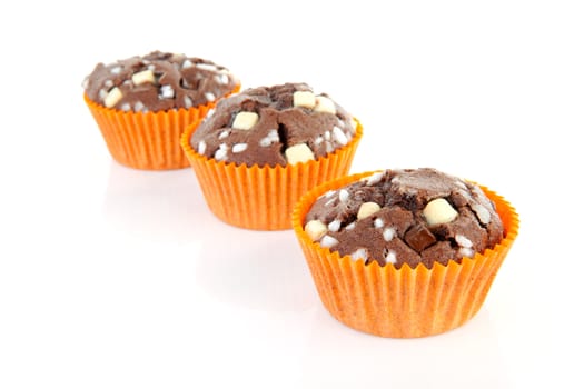 three brown home baked cupcake with chocolate pieces isolated on white background