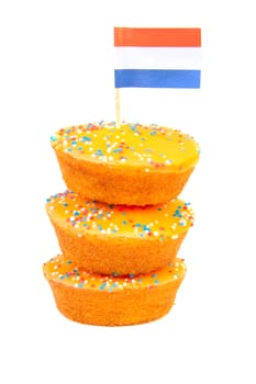 pile of orange cake cookies for Dutch soccer with confetti and flag over white background